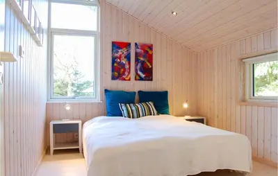 a bedroom with a white bed and two windows at Villa Mormor in Løkken