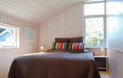a bedroom with a bed in a room with two windows at Villa Mormor in Løkken