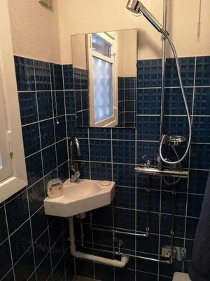 a blue tiled bathroom with a sink and a mirror at Enkeltværelse in Vestervig