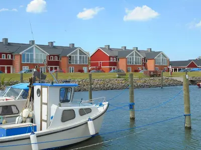 a boat docked in the water in front of houses at 4 person holiday home on a holiday park in Lemvig in Lemvig