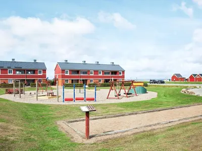 a playground in front of a red building at 4 person holiday home on a holiday park in Lemvig in Lemvig