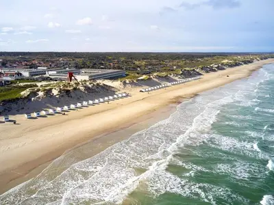 an aerial view of a beach with umbrellas and the ocean at 6 person holiday home on a holiday park in Blokhus in Blokhus