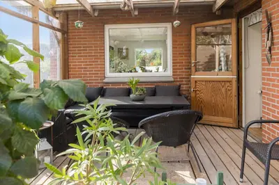 a patio with a table and chairs on a porch at Logi i hus med kunst og have in Vestervig