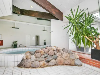 a pool in a room with a large rock formation at 6 person holiday home in Brovst in Brovst