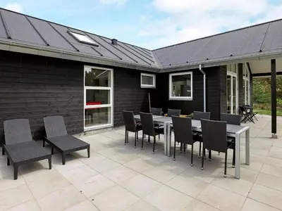 a patio with a table and chairs and a building at 10 person holiday home in Thisted in Thisted