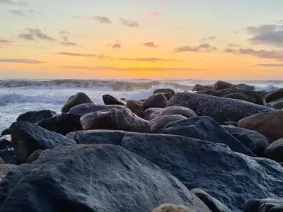 a group of rocks on the beach at sunset at 10 person holiday home in Thisted in Thisted
