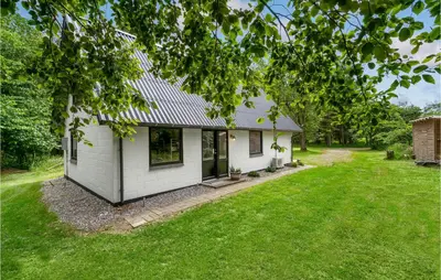 a small white house with a grass yard at Cozy Home In Øster Assels With Sauna in Øster Assels