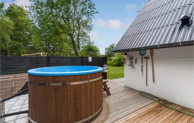 a hot tub on a deck next to a building at Cozy Home In Øster Assels With Sauna in Øster Assels