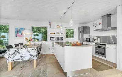 a white kitchen with a table and a dining room at Amazing Home In Roslev With Wifi in Roslev