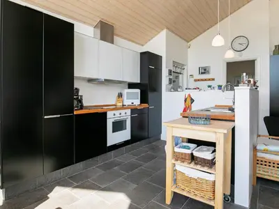 a kitchen with black and white cabinets and a table at 6 person holiday home in Brovst in Brovst