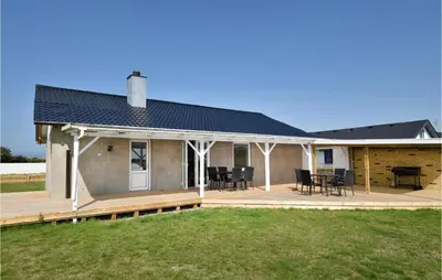a house with a deck with chairs and a table at Awesome Home In Harboøre With Kitchen in Harboør