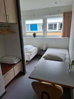 a room with two beds and a table and a mirror at Stoholm Vandrehjem in Stoholm