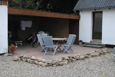 a patio with a table and chairs in front of a building at BrusaaUdlejning in Nibe