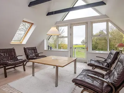 a living room with a table and chairs and windows at 8 person holiday home in Fur in Fur