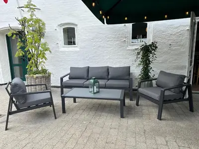 a patio with a couch and two chairs and a table at Hotel Steenbergs in Nykøbing Mors