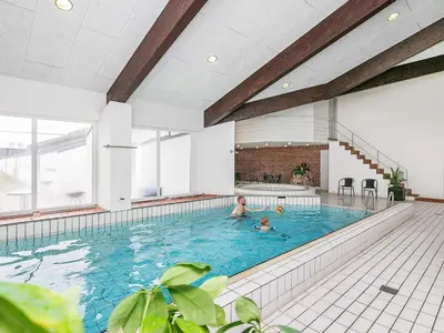 two people swimming in a large indoor swimming pool at Cozy Cottage in Skaven Strand-By Traum in Brovst