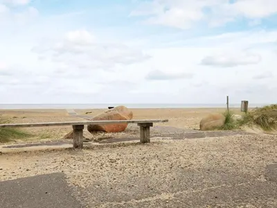 a bench on the beach with a large rock at Cozy Cottage in Skaven Strand-By Traum in Brovst