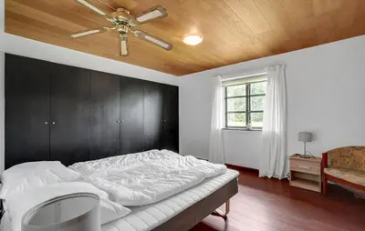 a bedroom with a bed with a ceiling fan at Sommerhus Farmen i Hanstholm in Hanstholm