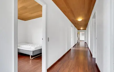 a hallway with a bed and white walls and wood floors at Sommerhus Farmen i Hanstholm in Hanstholm