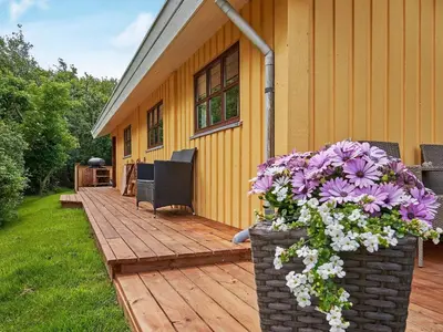 a house with a wooden deck with purple and white flowers at Cozy Coastal Cottage Retreat-By Traum in Sindrup