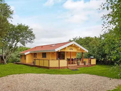 a small yellow house with a deck in a yard at Cozy Coastal Cottage Retreat-By Traum in Sindrup