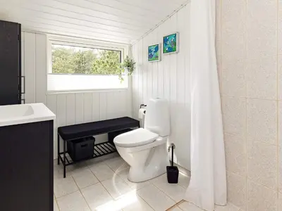 a bathroom with a toilet and a sink and a window at Bright Coastal Retreat in Vorupor-By Traum in Thisted