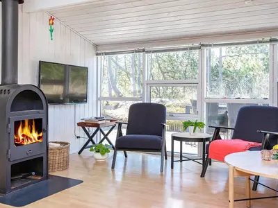 a living room with a fireplace and a table and chairs at Bright Coastal Retreat in Vorupor-By Traum in Thisted