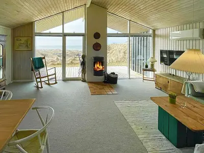 a living room with a fireplace and a table and chairs at 6 person holiday home in Løkken in Løkken