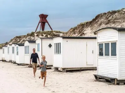 a man and a boy running on the beach at 8 person holiday home in Blokhus in Blokhus