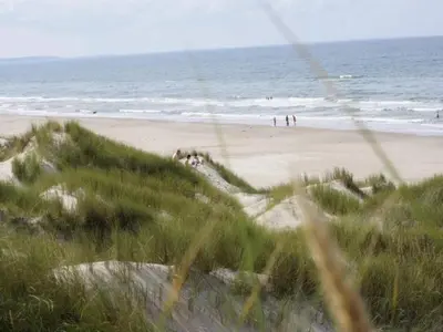 a beach with people on the sand and the ocean at Tranquil Retreat in Blokhus-By Traum in Blokhus