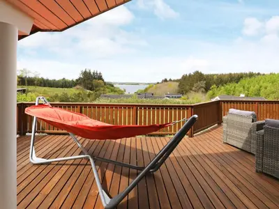 a red chair sitting on the deck of a house at 8 person holiday home in Skals in Skals