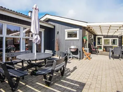 a patio with a table and chairs and an umbrella at Secluded Forest Haven-By Traum in Løgsted