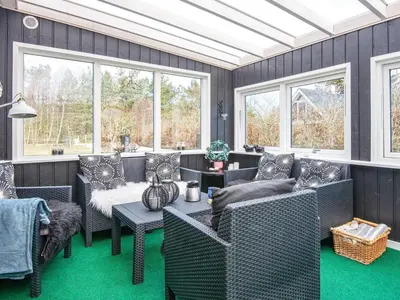 a living room with couches and a table and windows at Secluded Forest Haven-By Traum in Løgsted