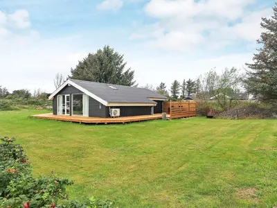 a small house in a yard with a grass field at Cozy Coastal Retreat in Gronhoj-By Traum in Løkken