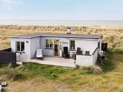 a white house on the beach near the ocean at 4 person holiday home in Fjerritslev in Fjerritslev