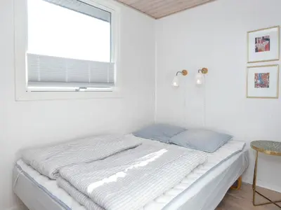a bed in a white room with a window at Family Holiday Home by North Sea in Lemvig