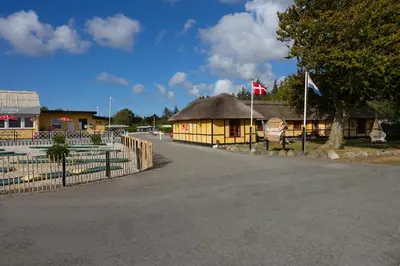 a small building with a flag and a fence at Bygholm Camping og aktiviteter in Vesløs