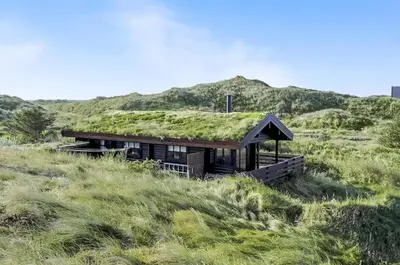 a house with a grass roof on top of a hill at Cozy house with stunning sea views in Pandrup