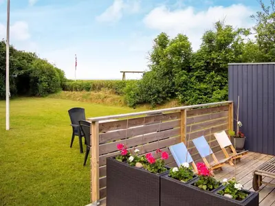 a patio with chairs and flowers on a deck at 6 person holiday home in Hurup Thy in Sønder Ydby