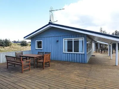 a blue building with a table and benches on a deck at 8 person holiday home in Løkken in Løkken