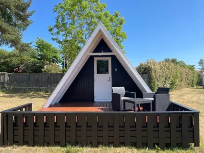 a pitched roof house with a deck and a table at Løgstør Camping in Løgstør