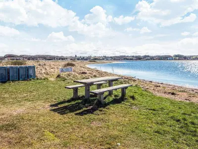 a picnic bench sitting on the grass near the water at 6 person holiday home in Højslev-By Traum in Højslev