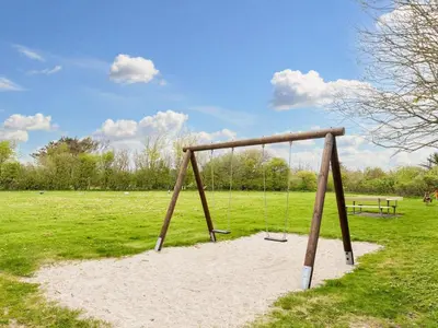 a swing set in a field with a bench at 6 person holiday home in Vestervig-By Traum in Vestervig