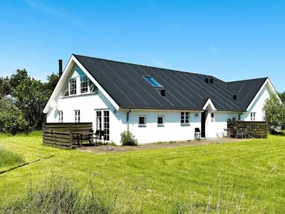 a white barn with a black roof on a field at 10 person holiday home in Thisted in Thisted