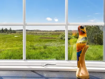 a colorful bird statue sitting in front of a window at 10 person holiday home in Thisted in Thisted