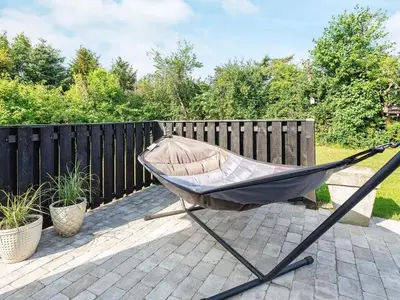 a hammock sitting on a patio next to a fence at 6 person holiday home in Løgstør in Løgstør