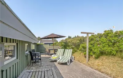 a patio with two lawn chairs and an umbrella at Holiday Home Porsevej Saltum in Saltum