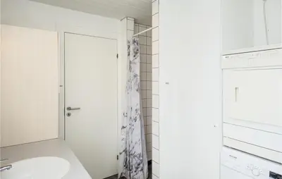 a white bathroom with a sink and a shower at Nice Home In Blokhus With Sauna in Blokhus