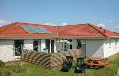 a house with a solar roof with a table and chairs at Nice Home In Blokhus With Sauna in Blokhus