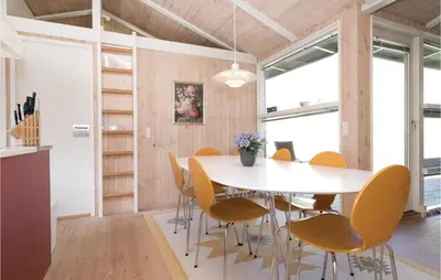 a dining room with a white table and yellow chairs at Holiday Home Moreavej in Blokhus